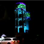 Artistic projection and lighting adorn the Goondiwindi MacLean Street water tower in blue green and purple.