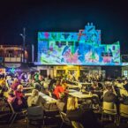Brightly hand drawn blooms are painted today and projected tonight on an art deco building at Bloomin' Birds Spring Festival in Coonabarabran