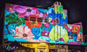 brightly hand drawn blooms projected on an art deco building at a festival